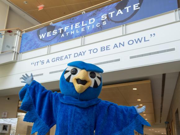 Nestor the Owl, with arms spread wide, beneath a sign that says, "It's a great day to be an owl"