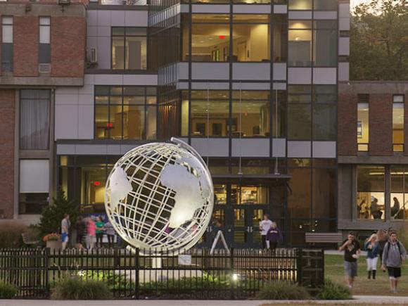 The metal globe sculpture on the Westfield State University campus is lit by spotlights at dusk.