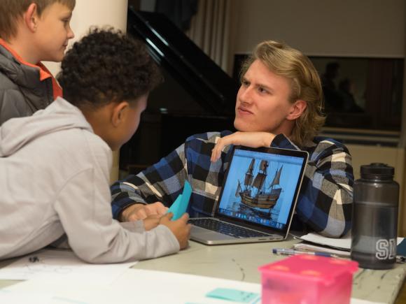 Education student teaching children on laptop