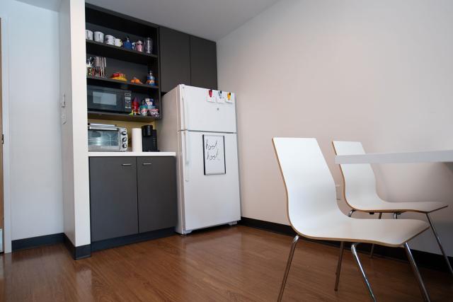 A shared kitchenette space with a full-sized refrigerator, microwave, and cupboard space.