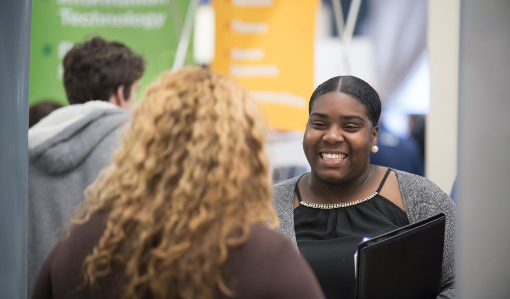 Smiling female talks with a prospective employer at the Career Fair